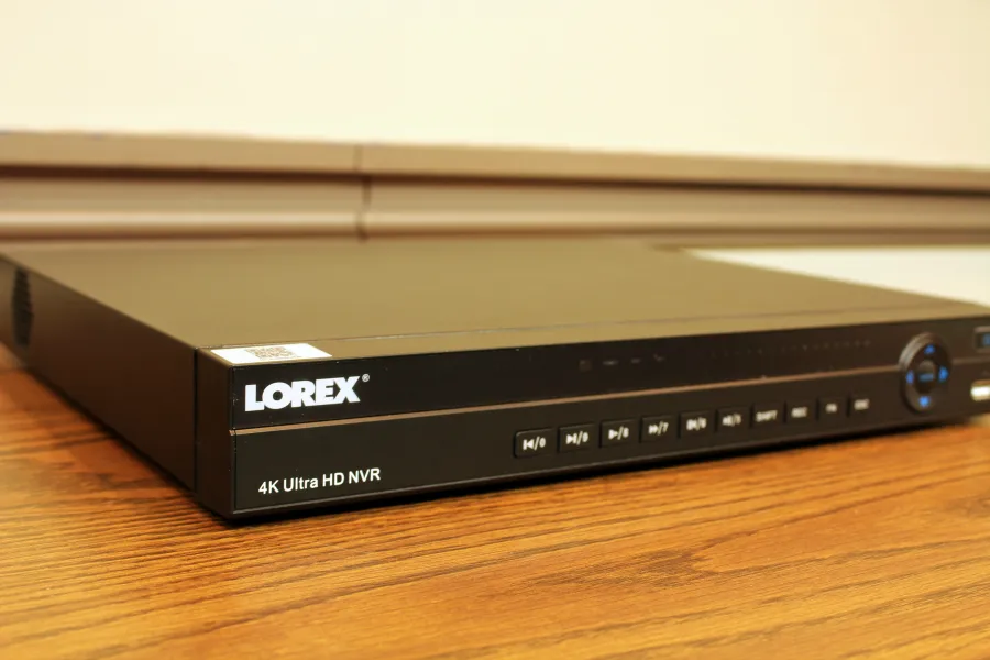 Black network video recorder with front panel buttons and a round blue control dial seen from the side