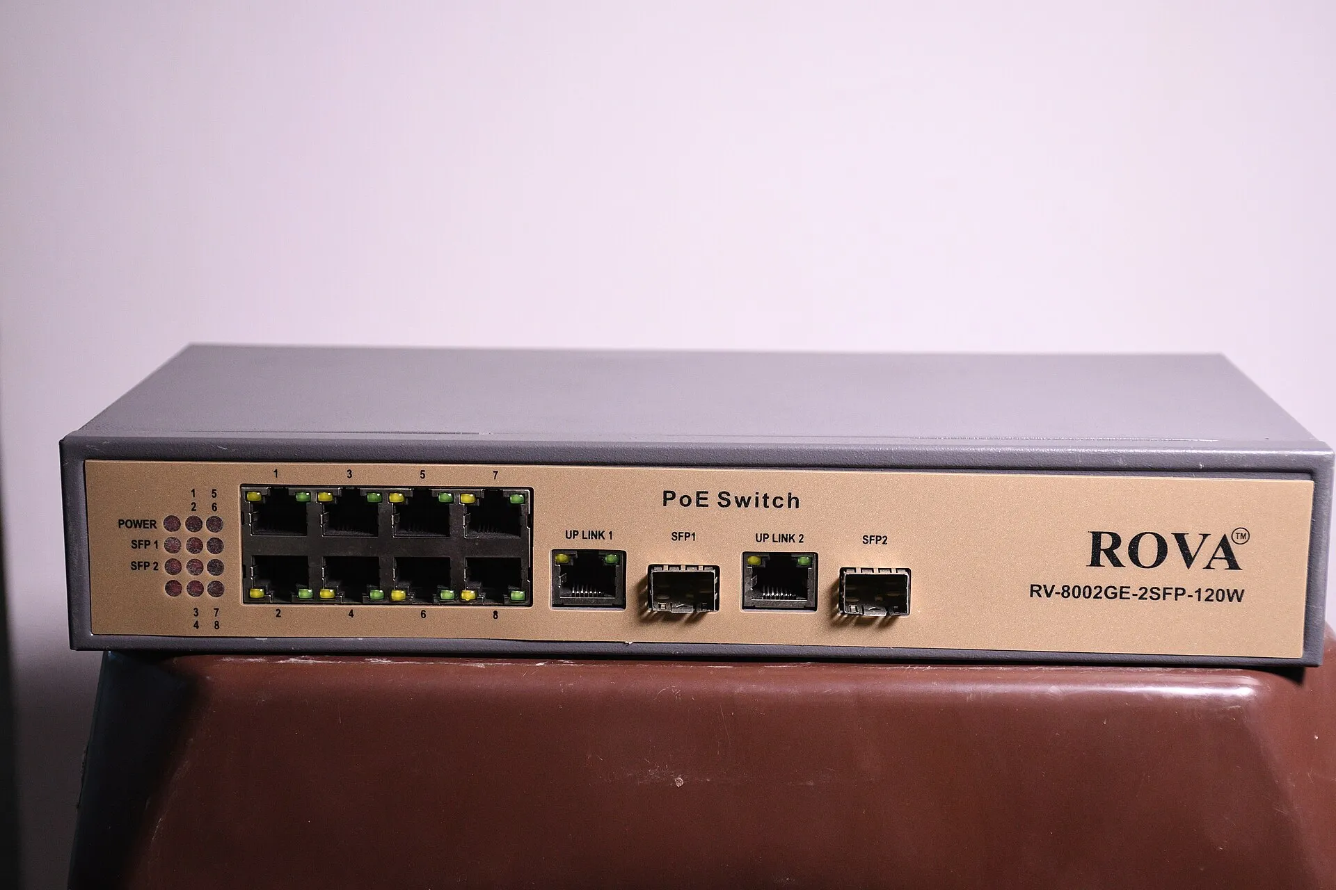 Grey eight port PoE switch with two uplink ports and two fibre sockets, seen from the front
