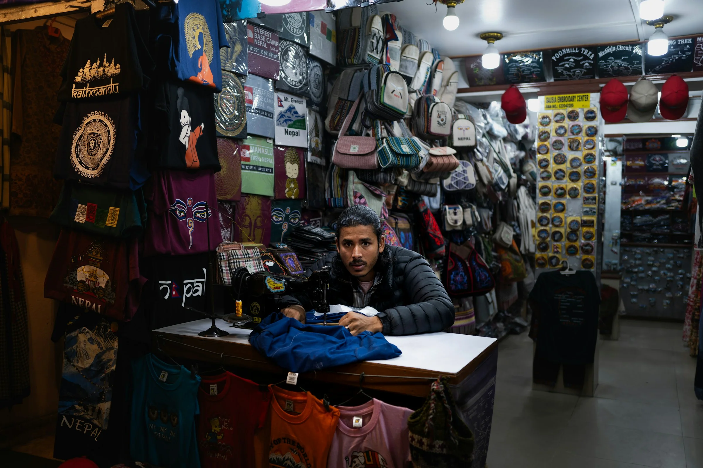 A man sitting at the counter of a crowded shop in Nepal