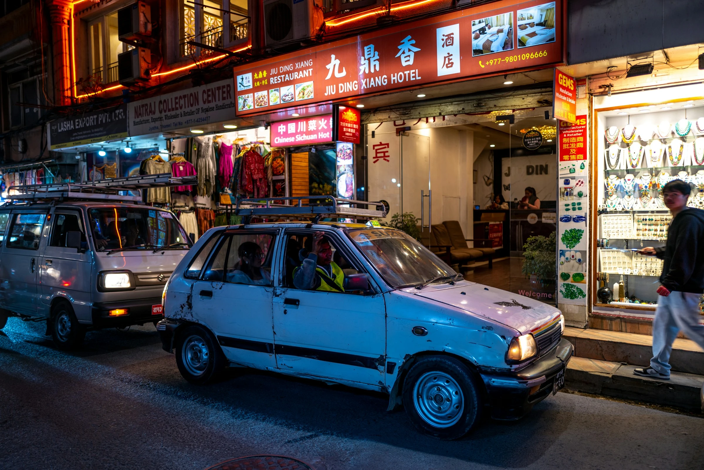 A night street in Thamel, Kathmandu, with shops and a taxi