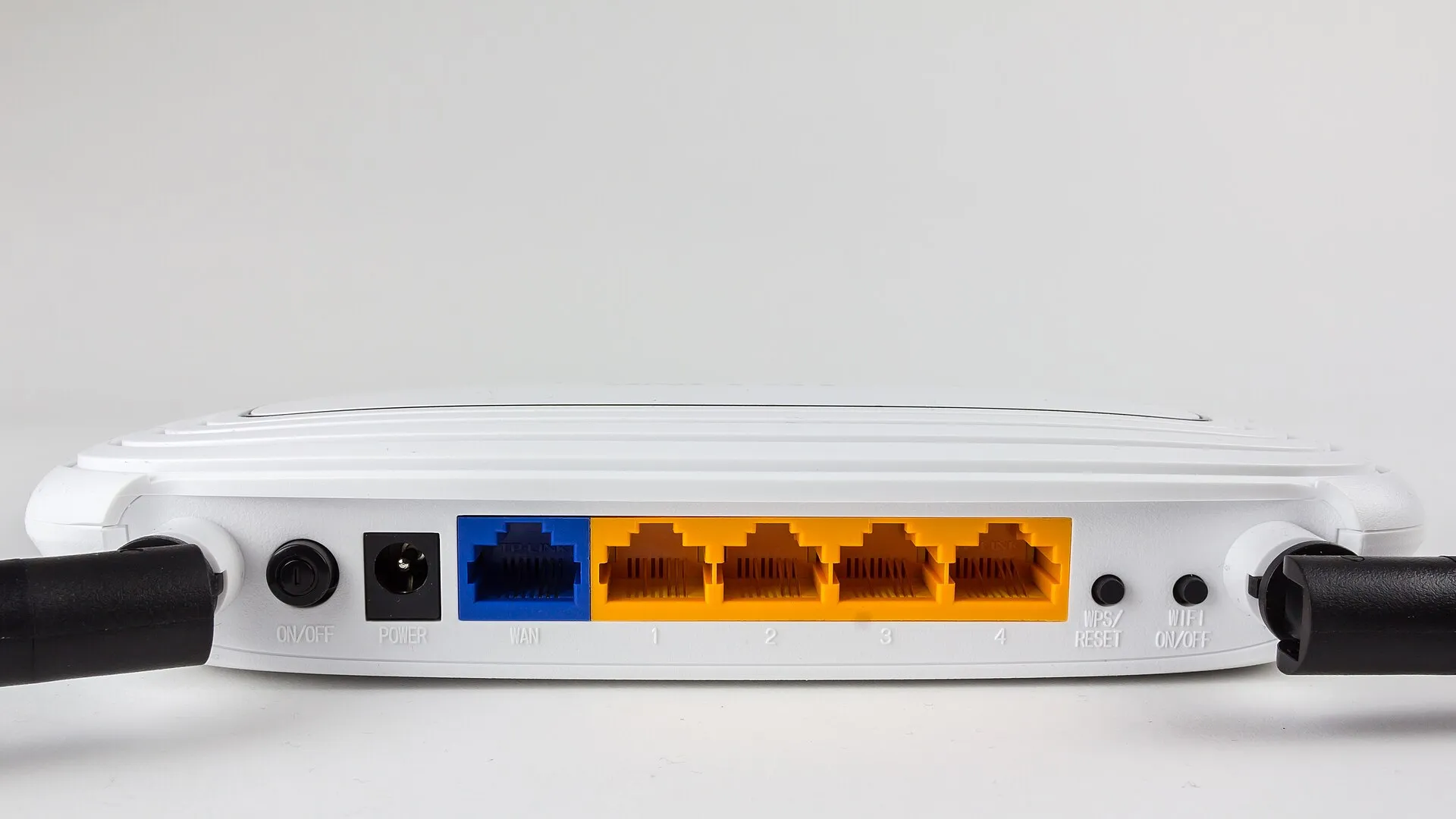 White TP-Link router seen from behind with one blue WAN port, four yellow LAN ports and a WPS reset button